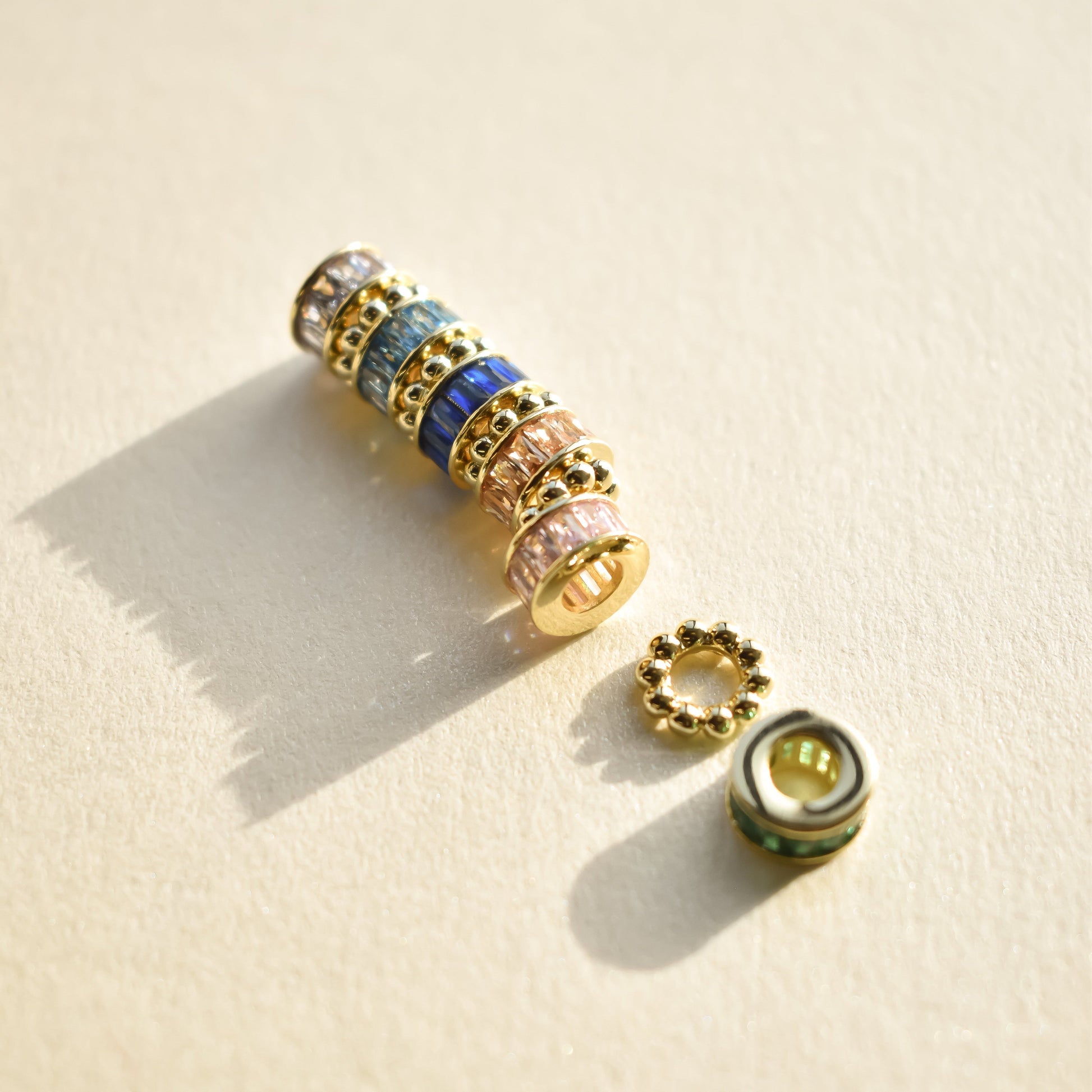 Gold beaded bracelet with multicolored beads on a beige background